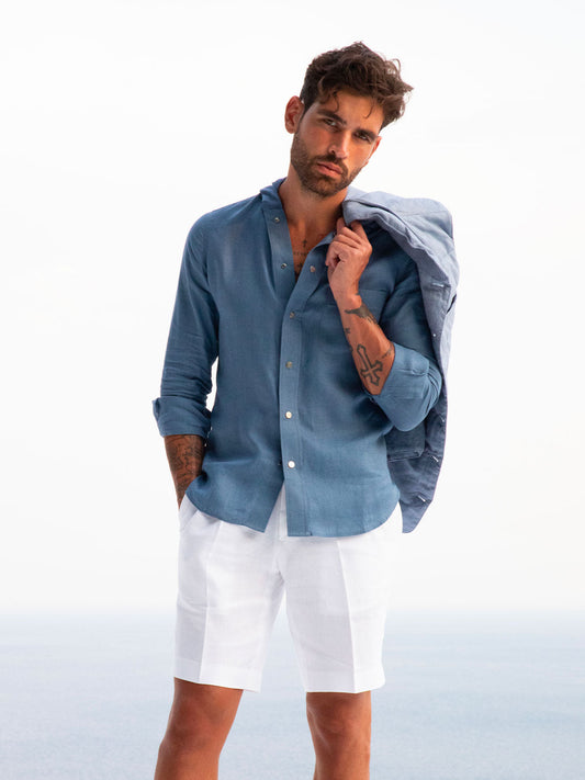 Model wearing Capri® white linen bermuda shorts in resort setting – 100% Capri
