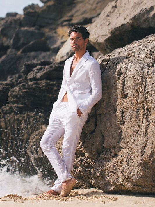 Model wearing St Tropez white linen jacket in resort setting – 100% Capri